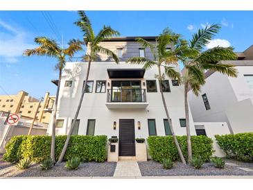 Modern three-story home featuring palm trees, a balcony, and a well-maintained front yard with stone details at 325 2Nd N St, St Petersburg, FL 33701