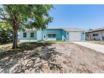 Charming single-story home featuring a light blue exterior, well-maintained lawn, and a driveway leading to an attached garage at 4307 Woodfield Ave, Holiday, FL 34691