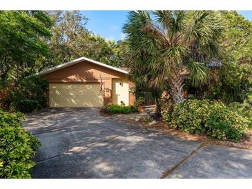 Charming single-story home featuring a two-car garage, a mature palm tree, and lush landscaping at 50 Pembrook Cir, Palm Harbor, FL 34683