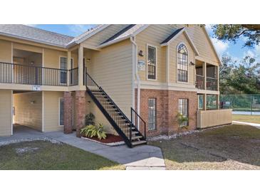 Inviting condo complex exterior featuring brick accents, well-maintained landscaping, and convenient staircase access at 8724 Mallard Reserve Dr # 101, Tampa, FL 33614
