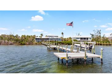 Waterfront home featuring private dock and boat lift with an American flag waving in the background at 9048 Wharf Ave, Placida, FL 33946
