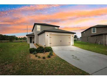 Inviting two-story home featuring a well-manicured lawn and a two-car garage under a colorful sunset at 14100 Holly Hammock Ln, Brooksville, FL 34613