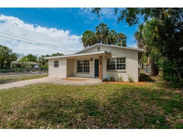 Charming home featuring a well-manicured lawn, brick walkway, neutral paint, and mature landscaping at 1923 W State St, Tampa, FL 33606