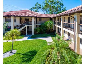 Inviting condo exterior with lush landscaping, red tile roof, and multiple floors of units at 2213 Hammock Pine Blvd, Clearwater, FL 33761
