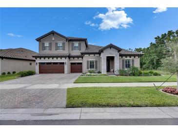 Charming two-story home with gray stucco, tile roof, stone accents, and a manicured lawn at 14421 Swiss Bridge Dr, Lithia, FL 33547