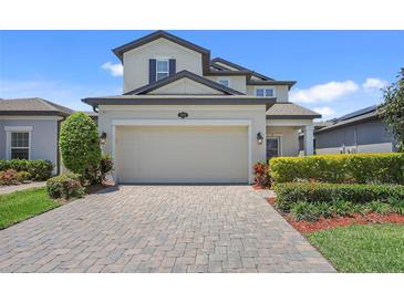 Two-story home featuring a paved driveway leading to an attached two-car garage and landscaped yard at 1949 Parterre Ave, Lutz, FL 33558