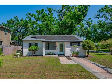 Charming home with a brick pathway, white painted brick, solar panels, and tidy landscaping at 701 W Idlewild Ave, Tampa, FL 33604