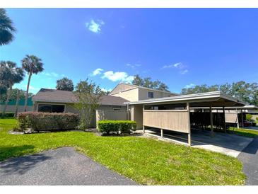 Quaint one-story home with lush landscaping, carport, and beige exterior at 7939 Pine Dr # 7939, Temple Terrace, FL 33637
