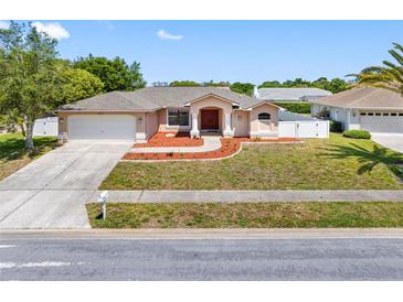Charming single Gathering home featuring a well-manicured lawn and a two-car garage at 1061 Archway Dr, Spring Hill, FL 34608