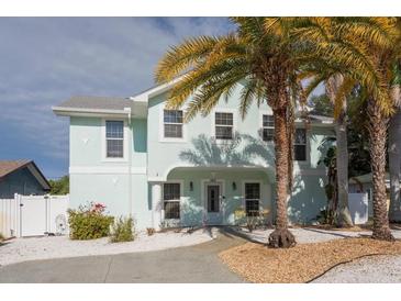 Inviting two-story light blue home with a walkway and lush palm trees in the front yard at 1411 Gray S St, Gulfport, FL 33707