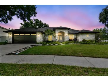 Beautiful single-story home with a well-manicured lawn and welcoming curb appeal at twilight at 1727 Woodpond Way, Lutz, FL 33559