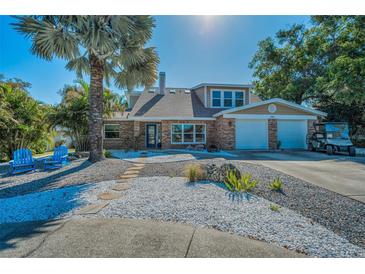 Charming brick home with lush landscaping, a two-car garage and a serene walkway at 508 N Mayo St, Crystal Beach, FL 34681