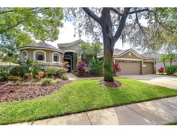 Charming single-Gathering home showcasing a well-manicured lawn and lovely landscaping with a three car garage at 6112 Ibispark Dr, Lithia, FL 33547