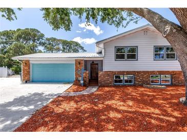 Charming two-story home boasts colorful garage door, brick accents, and lush landscaping at 6515 Dimarco Rd, Tampa, FL 33634