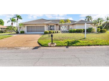 Charming one-story home featuring a tile roof, manicured lawn, and a two-car garage at 6994 Country Lakes Cir, Sarasota, FL 34243