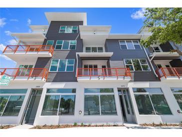 Modern multi-story building featuring orange balcony railings and large retail windows at 11 29Th N St, St Petersburg, FL 33713