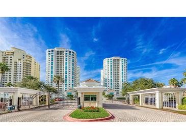 Elegant condos feature a gated entrance, manicured landscaping and stunning architecture under a clear blue sky at 1180 Gulf Blvd # 202, Clearwater Beach, FL 33767
