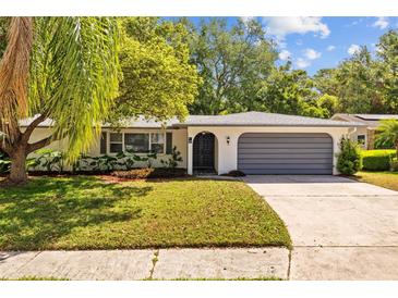 Charming single-story home with a well-manicured lawn, gray garage door, and an arched entryway at 1905 Oro Ct, Clearwater, FL 33764
