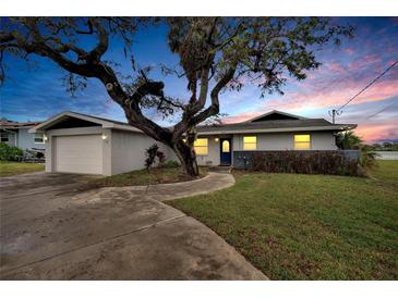 Charming single-story home with mature landscaping, attached garage, and inviting walkway at sunset at 828 Bayshore Dr, Tarpon Springs, FL 34689
