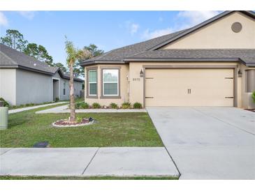Charming single-story home with a two-car garage and manicured lawn and an accent tree at 8975 Southern Charm Cir, Brooksville, FL 34613