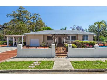 Charming home featuring a white fence, pergola entrance, well-maintained landscaping, and a convenient carport at 101 Pampas Ave, Tarpon Springs, FL 34689