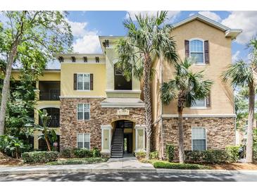Attractive condo building with stone accents, palm trees, and a well-maintained landscape at 10103 Courtney Oaks Cir # 103, Tampa, FL 33619