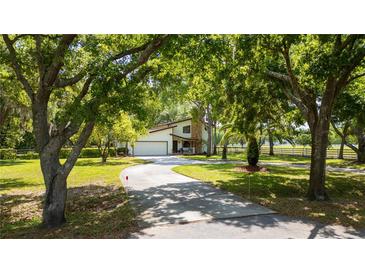Beautiful exterior view of home showing the driveway leading up to the garage surrounded by mature trees at 1691 Ridge Top Dr, Tarpon Springs, FL 34688