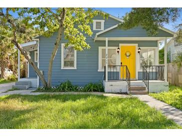 Charming home featuring a cheerful yellow front door and well-maintained lawn at 2215 Thrace St, Tampa, FL 33605