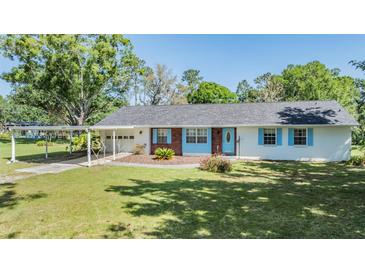 Charming single-story home features a brick facade and lovely blue shutters and door at 23701 Harmony Ln, Land O Lakes, FL 34639