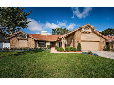 Charming single-Gathering home featuring a well-manicured lawn, brick accents and a clay tile roof at 2392 Hillcreek E Cir, Clearwater, FL 33759