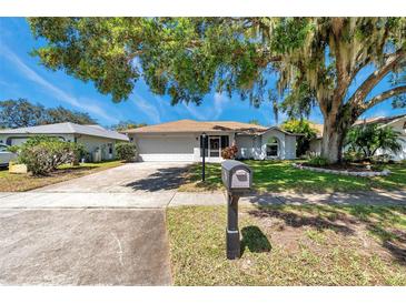 Charming single-story home with a well-manicured lawn and mature shade trees in a quiet neighborhood at 3957 Tarpon Pointe Cir, Palm Harbor, FL 34684