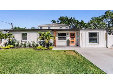 Charming single-story home featuring an orange front door, manicured lawn, and modern accents at 401 N Manhattan Ave, Tampa, FL 33609