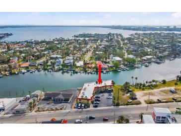 Aerial view of a yellow condo building near the water, featuring a serene coastal setting at 4103 Gulf Blvd # 106, St Pete Beach, FL 33706