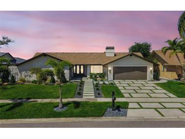 Charming single-story home featuring a manicured lawn, stone accents, and a modern driveway with integrated greenery at 4204 Saltwater Blvd, Tampa, FL 33615