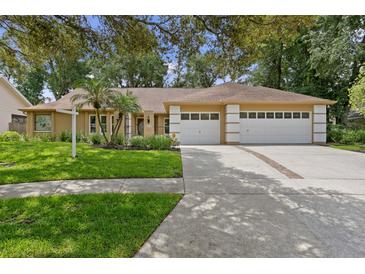 Charming single-story home featuring a three-car garage, lush lawn, and well-manicured landscaping at 6213 S Queensway Dr, Temple Terrace, FL 33617