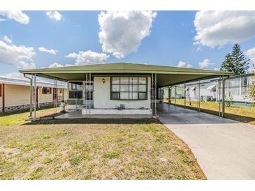 Charming single-story home with an awning, well-maintained lawn, and spacious driveway at 7045 El Dewitt St, Zephyrhills, FL 33541