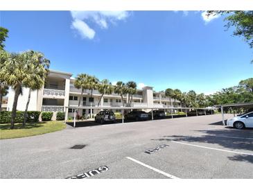 Condominium building with covered parking, palm trees, and a bright blue sky at 940 Virginia St # 304, Dunedin, FL 34698