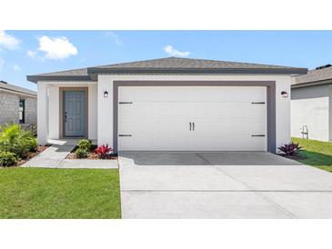 Charming one-story home featuring a two-car garage, a blue front door and manicured landscaping at 29535 Fedora Cir, Brooksville, FL 34602
