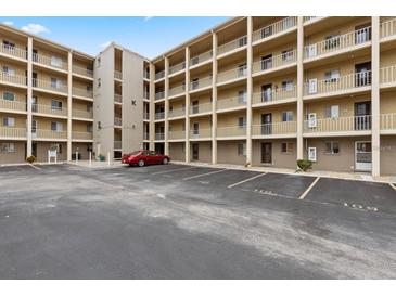 Exterior view of condo building with parking, multiple stories, and balconies under a blue sky at 3516 Lake Bayshore Dr # K109, Bradenton, FL 34205