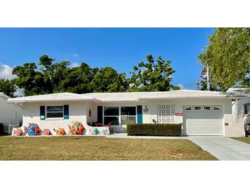 Charming single story home featuring tropical-themed decorations, manicured lawn, and a bright white exterior at 9308 45Th N St, Pinellas Park, FL 33782