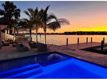 Inviting waterfront pool with modern lounge chairs at sunset reflecting off the pool and channel at 1493 Sea Gull S Dr, St Petersburg, FL 33707