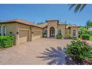 Beautiful home featuring arched windows, a double-door entry, and a brick driveway leading to a two-car garage at 20142 Lace Cascade Rd, Land O Lakes, FL 34637