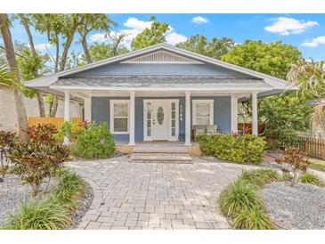 Charming home featuring a landscaped yard, brick walkway, and covered front porch at 7708 N Arden Ave, Tampa, FL 33604