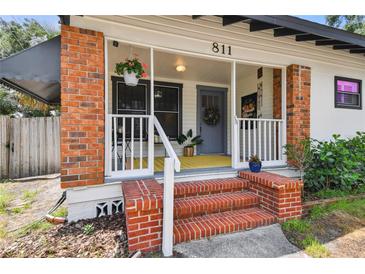 Charming front porch with brick stairs and columns, with hanging plants and a colorful rug at 811 E Flora St, Tampa, FL 33604
