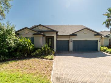 Charming single-story home featuring a two-car garage, paver driveway, and lush landscaping at 10404 Scarlet Chase Dr, Riverview, FL 33569