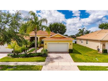 Beautiful single Gathering home featuring a brick driveway, two car garage, and lush tropical landscaping at 16261 Amethyst Key Dr, Wimauma, FL 33598