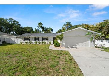 Charming single-story home with a two-car garage, well-maintained lawn, and tropical landscaping in a sunny, inviting setting at 1698 Eden Ct, Clearwater, FL 33756