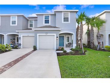 Charming two-story townhome with a one-car garage, blue front door, and well-maintained landscaping at 2265 Alee Ln, Wesley Chapel, FL 33543