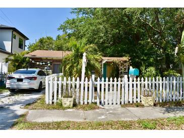 Charming home with a white picket fence, mature landscaping and a parked car visible from the street at 5045 2Nd S Ave, St Petersburg, FL 33707