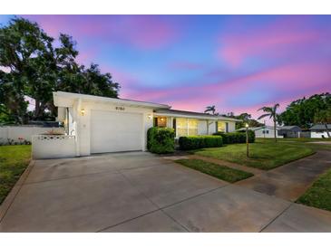 Charming single-story home with well-manicured lawn and mature landscaping under a colorful evening sky at 6160 29Th N Ave, St Petersburg, FL 33710